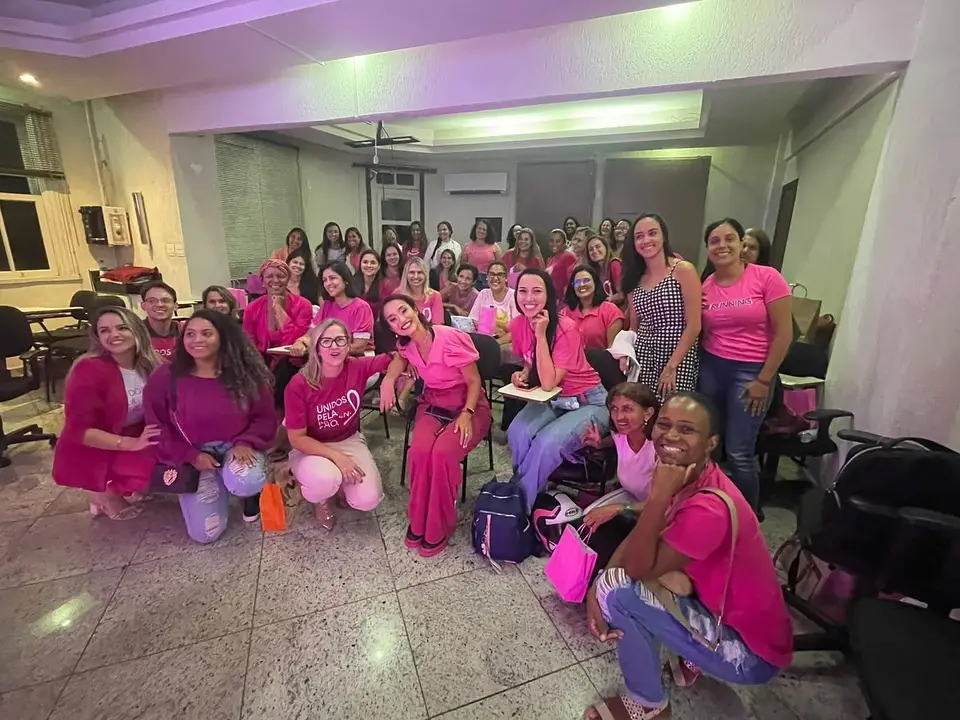 Sala cheia de alunas de rosa sorrindo durante um curso da AG Mama